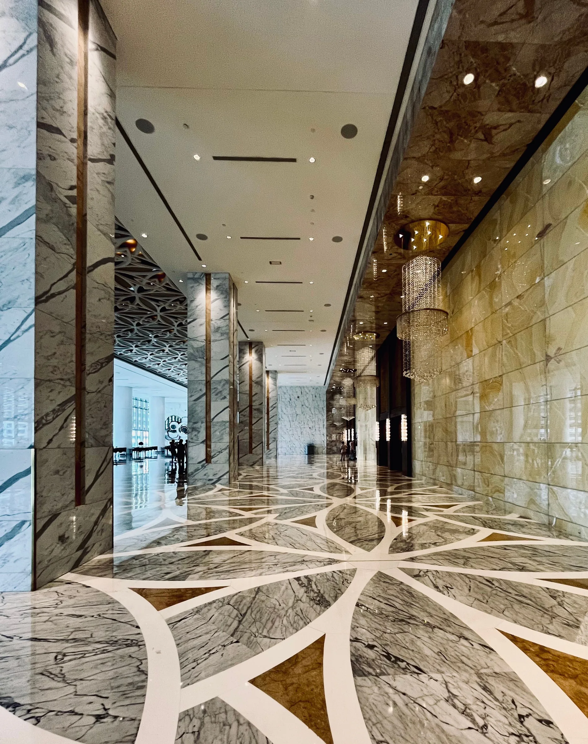 Hotellobby mit poliertem, geometrisch gemustertem Steinboden und Natursteinwänden