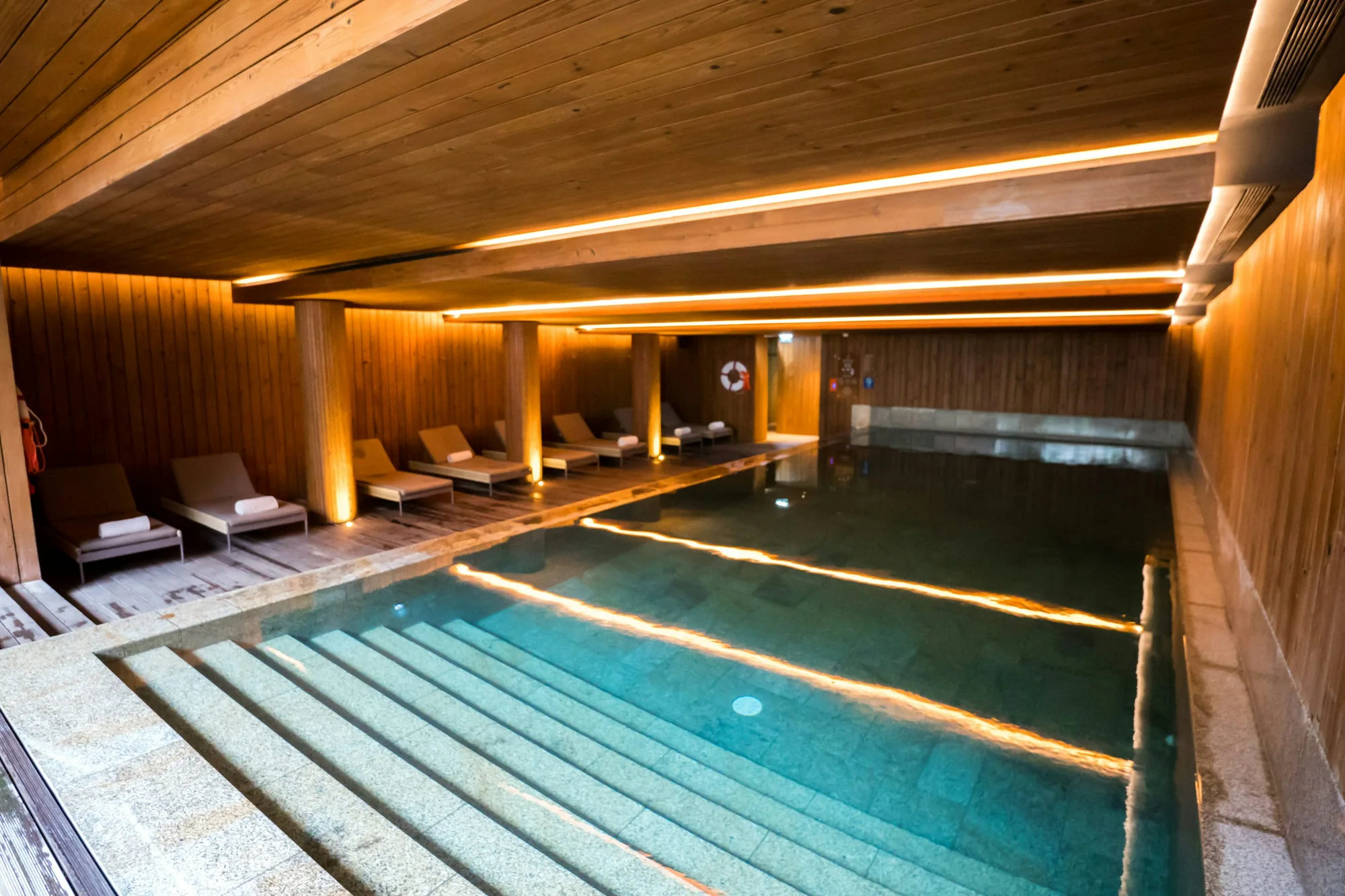 Indoor-Spa mit steinverkleidetem Pool und Liegebereich in warmem Licht
